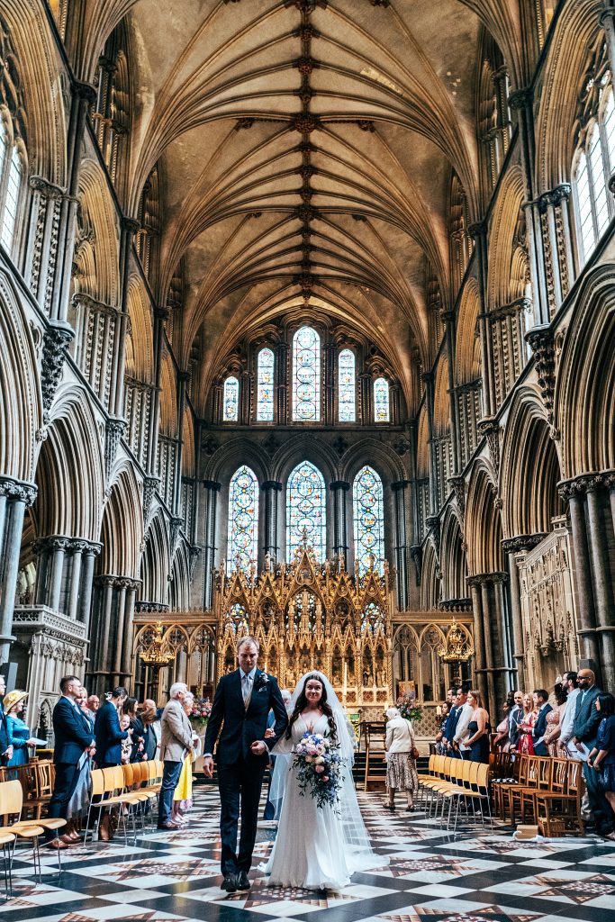 bride and groom walk up aisle at ELY cathedral