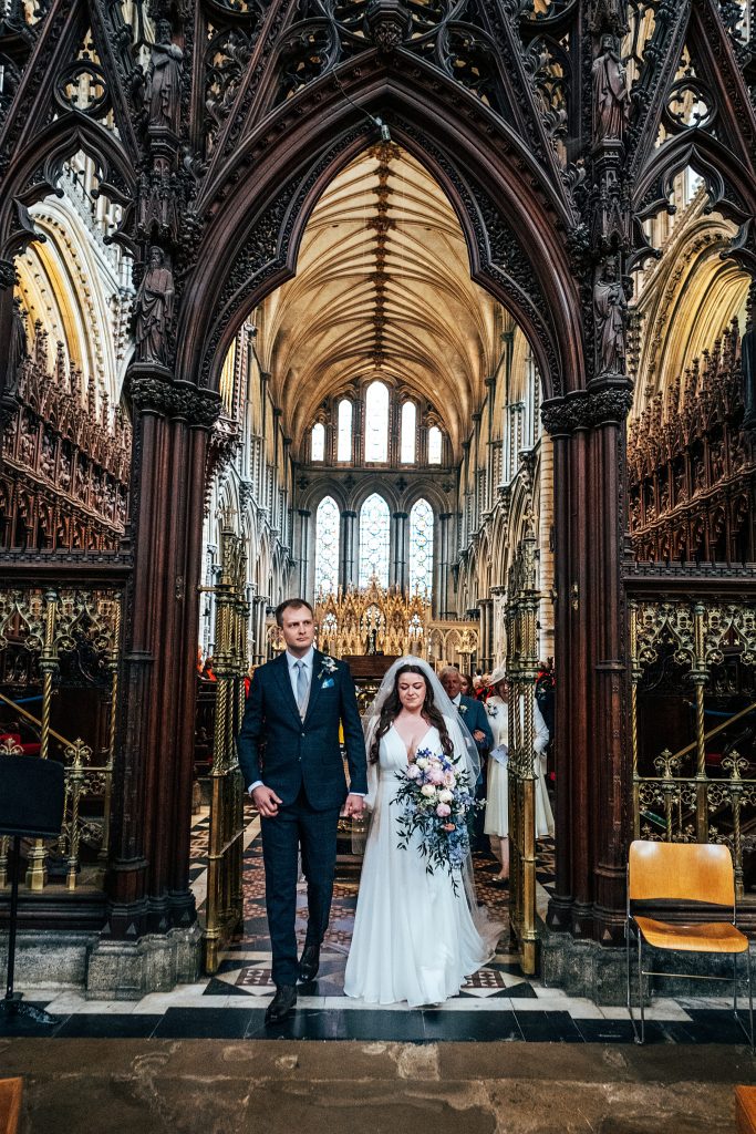 bride and groom walk up aisle at Ely Cathedral