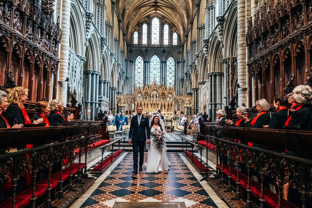 bride and groom walk up aisle at Ely Cathedral
