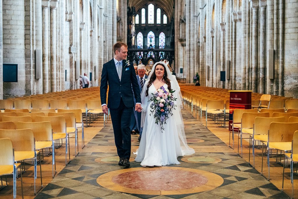 bride and groom walk up aisle at Ely cathedral