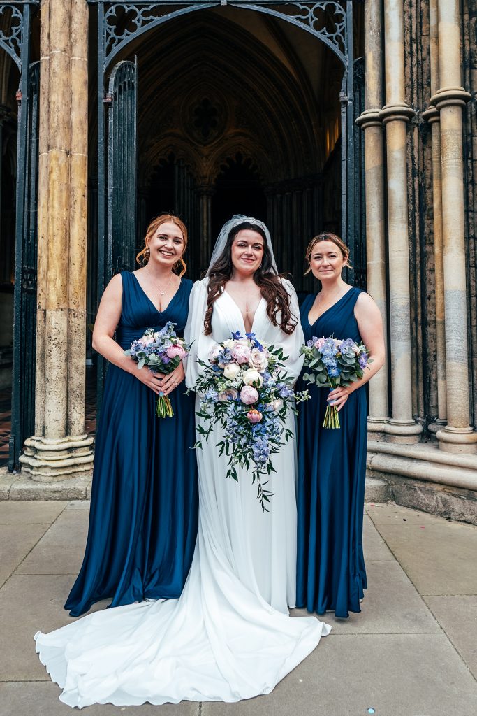 bride with bridesmaids in navy outside cathedral