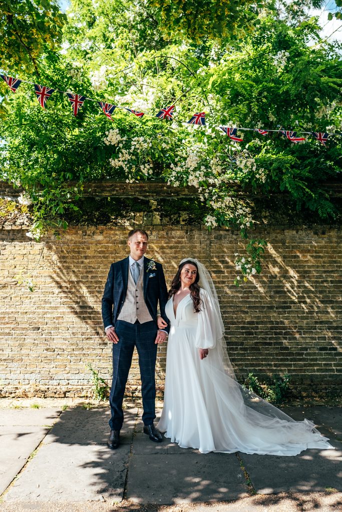 bride and groom stand in shade of tree