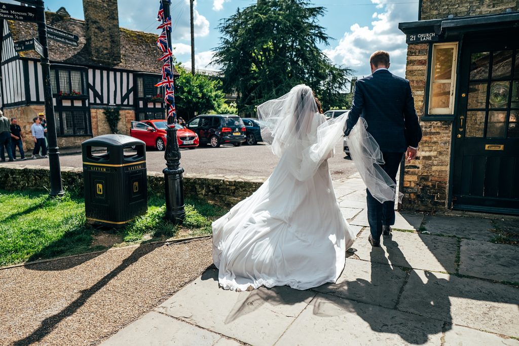 bride and groom walk to reception her veil and dress billowing behind