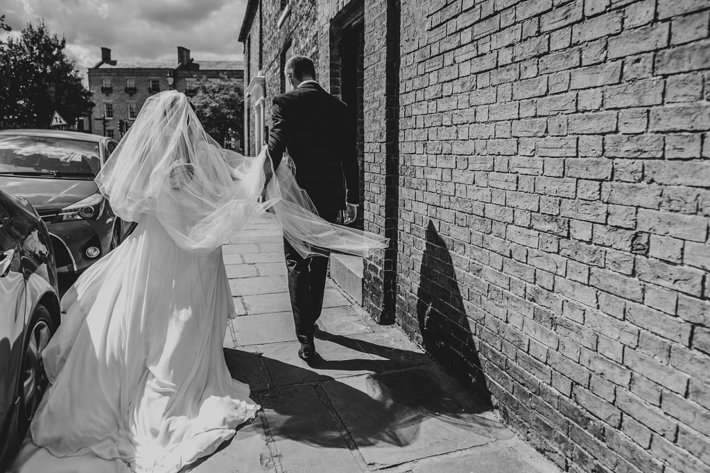 bride and groom walk to reception her veil and dress billowing behind