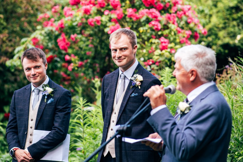 groom smiles during wedding speeches