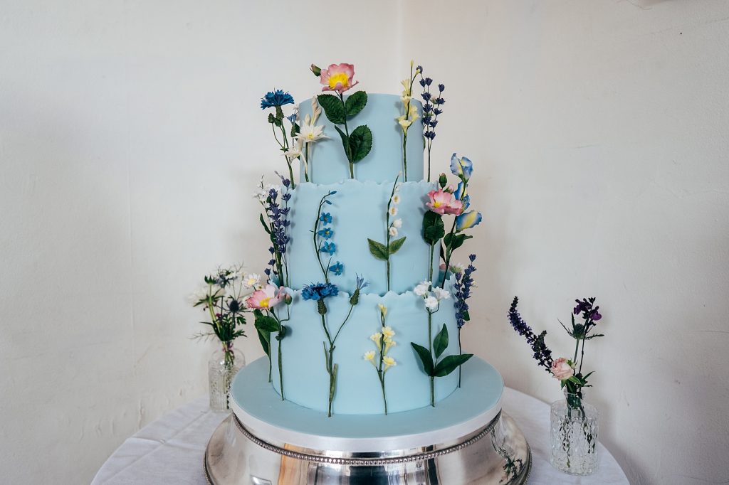 blue wedding cake decorated with wild flowers