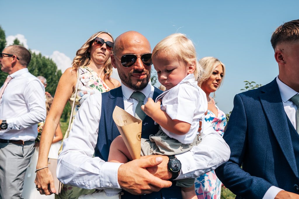 man in sunglasses holds little boy and confetti cone