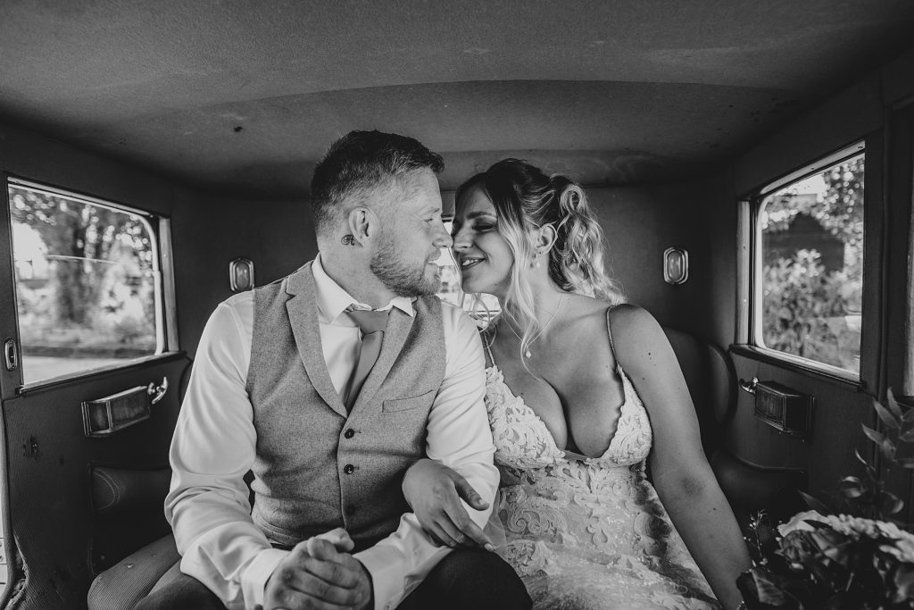 bride and groom sit in back of vintage car
