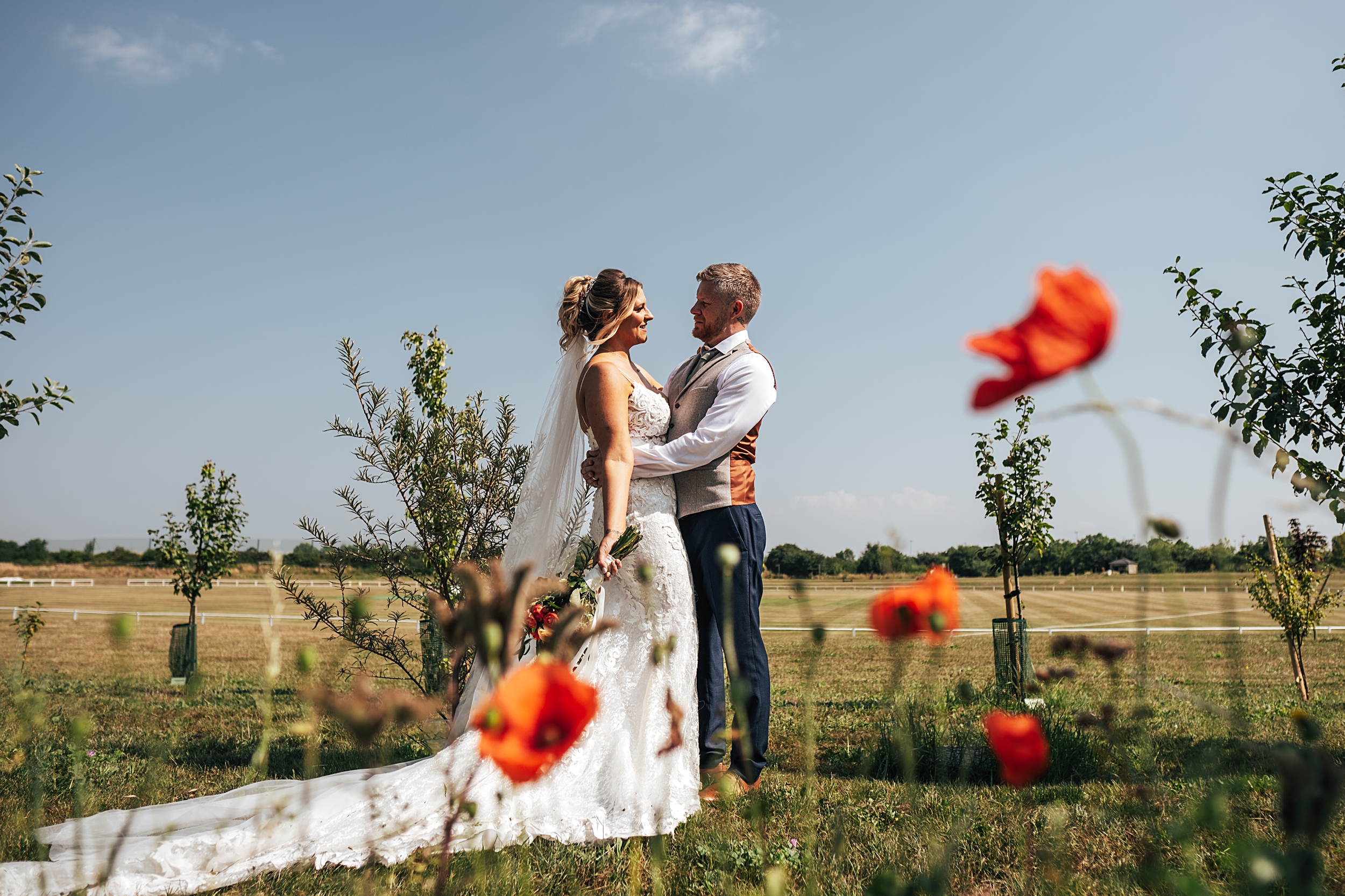 bride and groom stand together with poppies in foreground