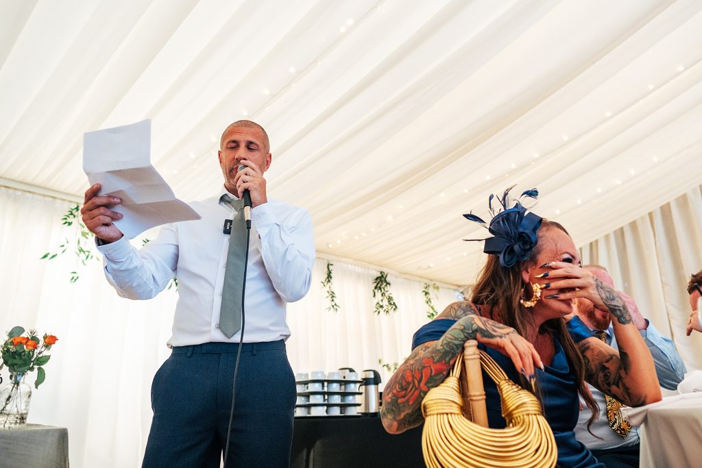 guest hides face and laughs during best man speech