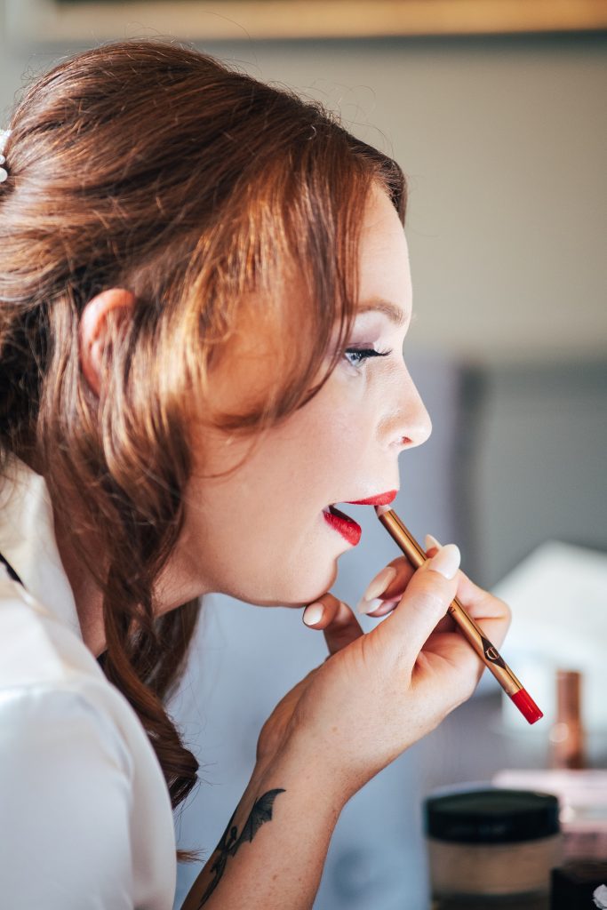 bride applies red lipstick