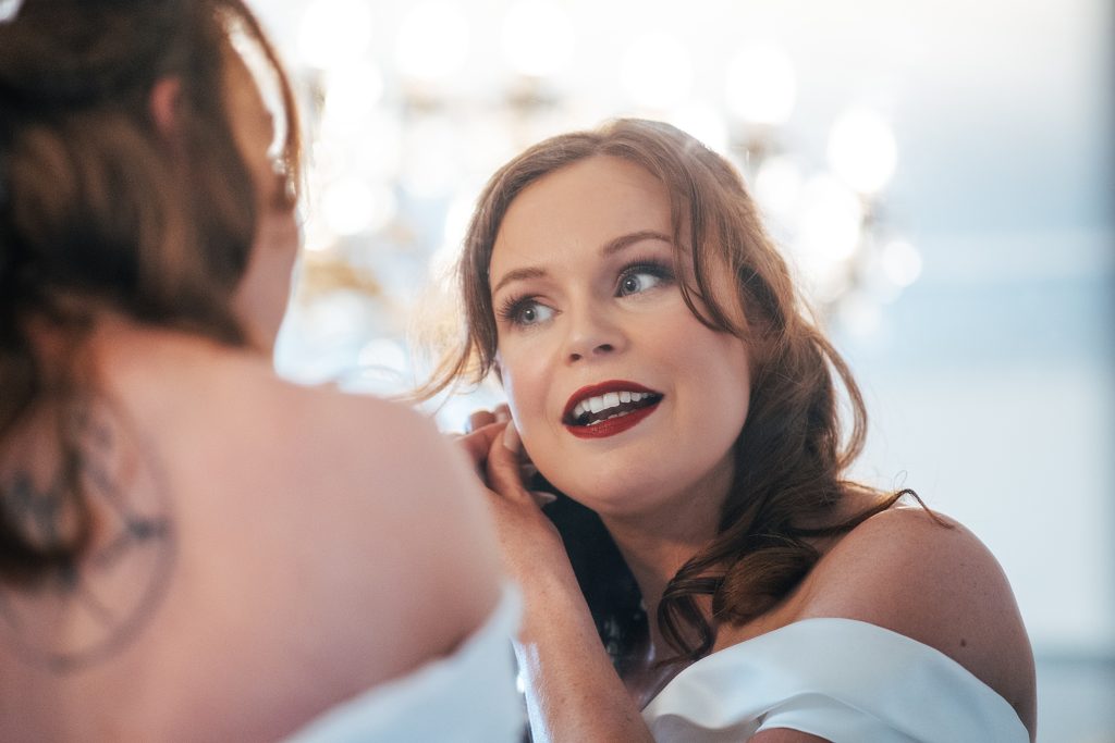 reflection of bride in mirror as she puts in earrings