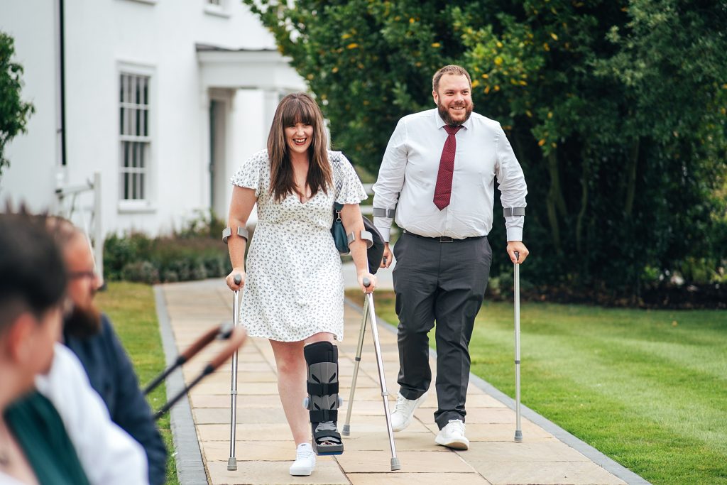 wedding guests both on crutches walk into ceremony