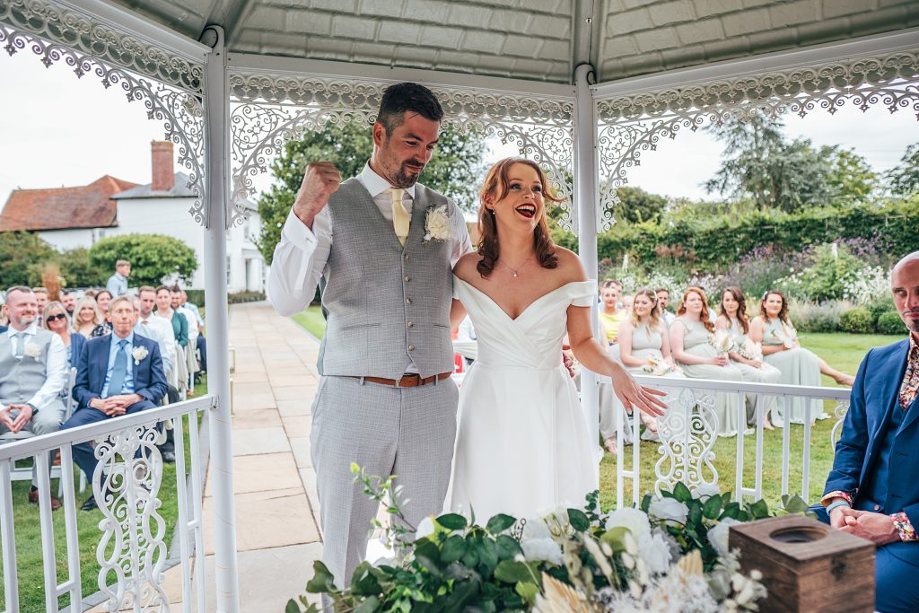 bride and groom laugh and wave arms and punch air