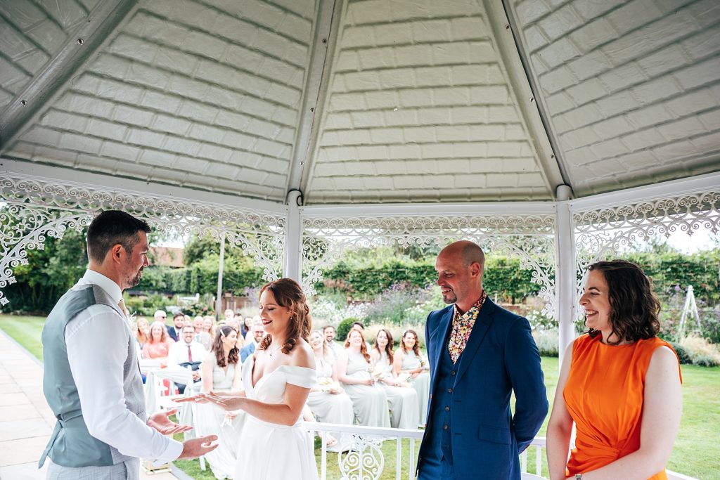 bride and groom with witnesses under pergola