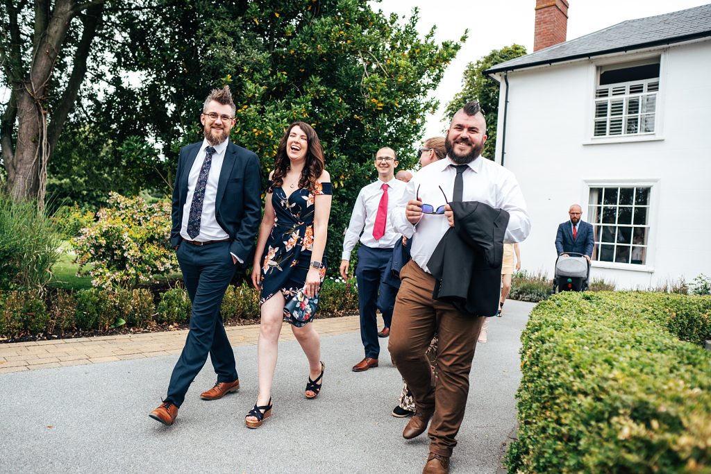 wedding guests laugh as they walk past camera