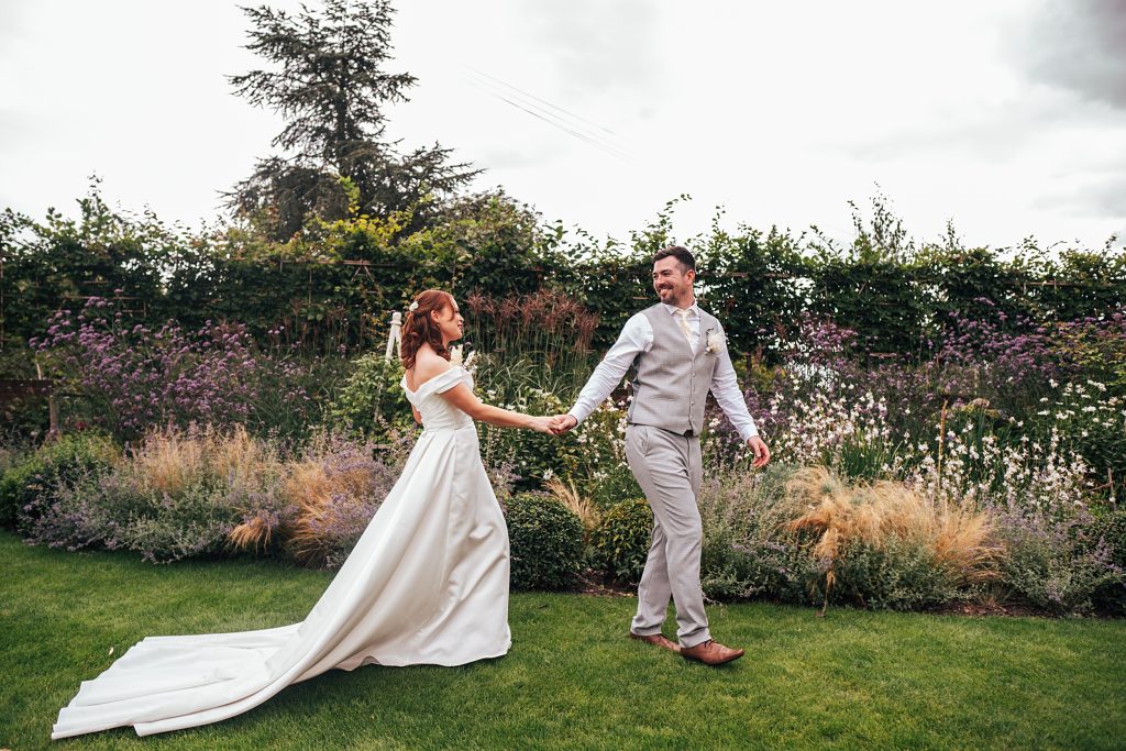 bride and groom walk in gardens