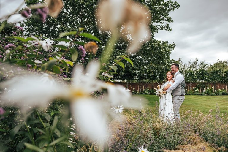 bride and groom in gardens with flowers in foreground