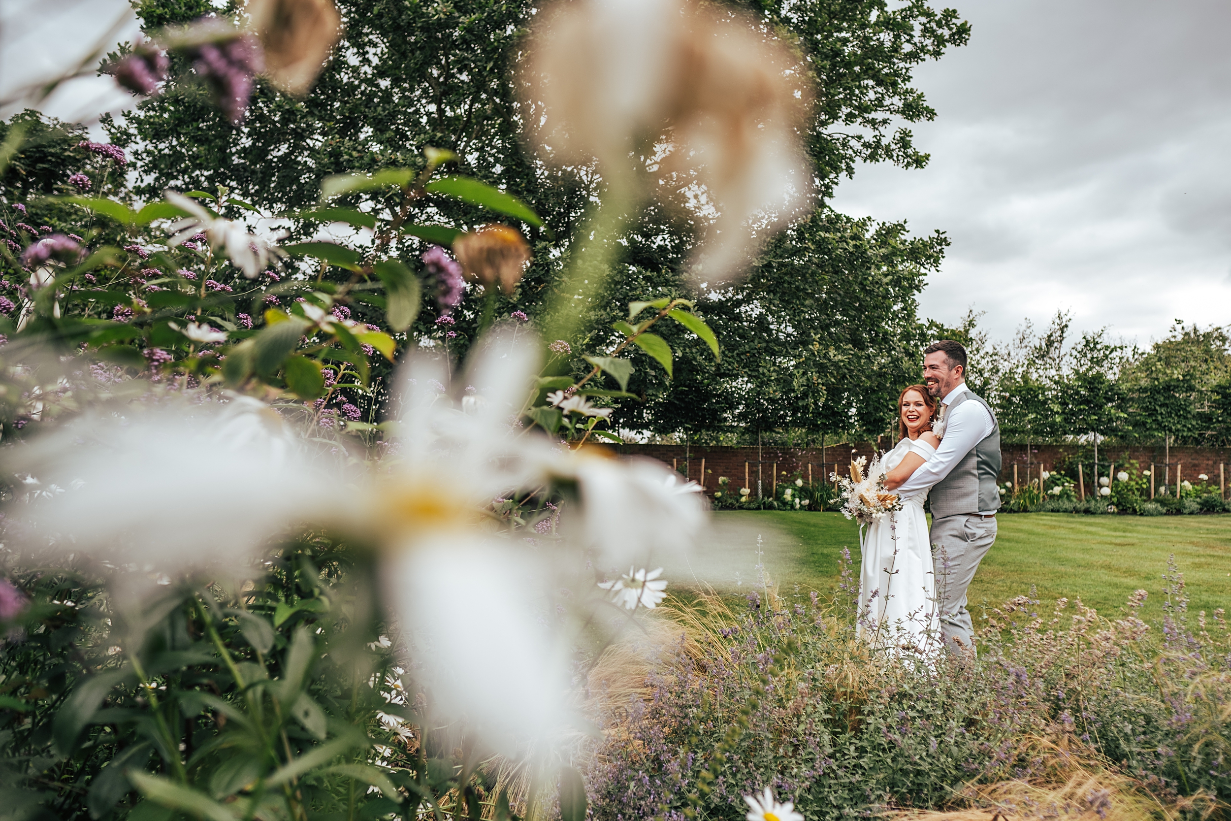 bride and groom in gardens with flowers in foreground