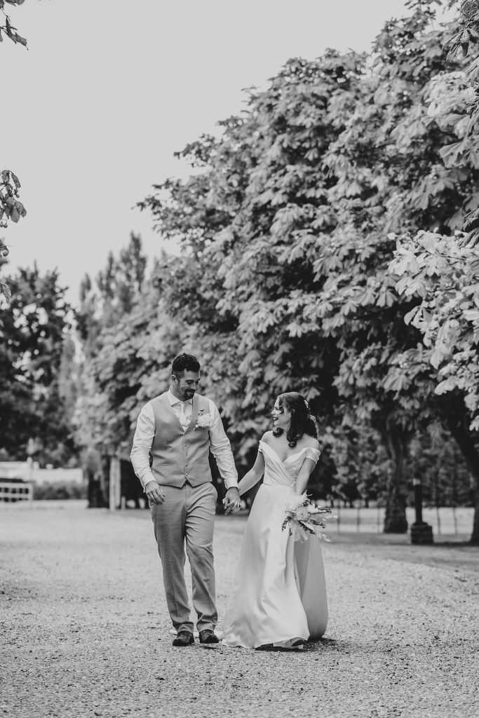 bride and groom walk treelined driveway