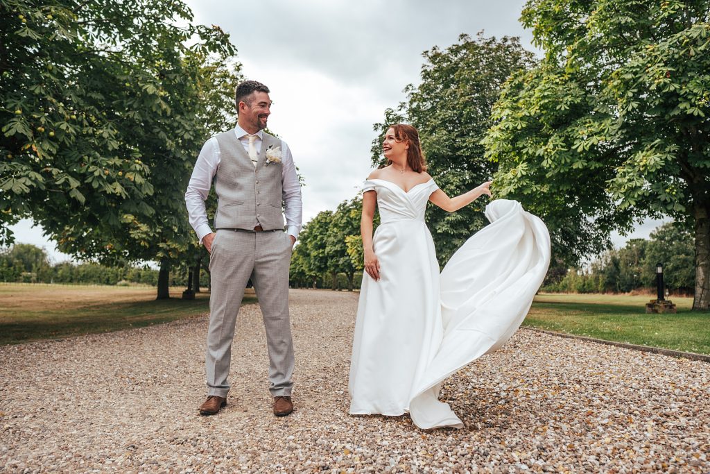 bride and groom stand on treelined driveway
