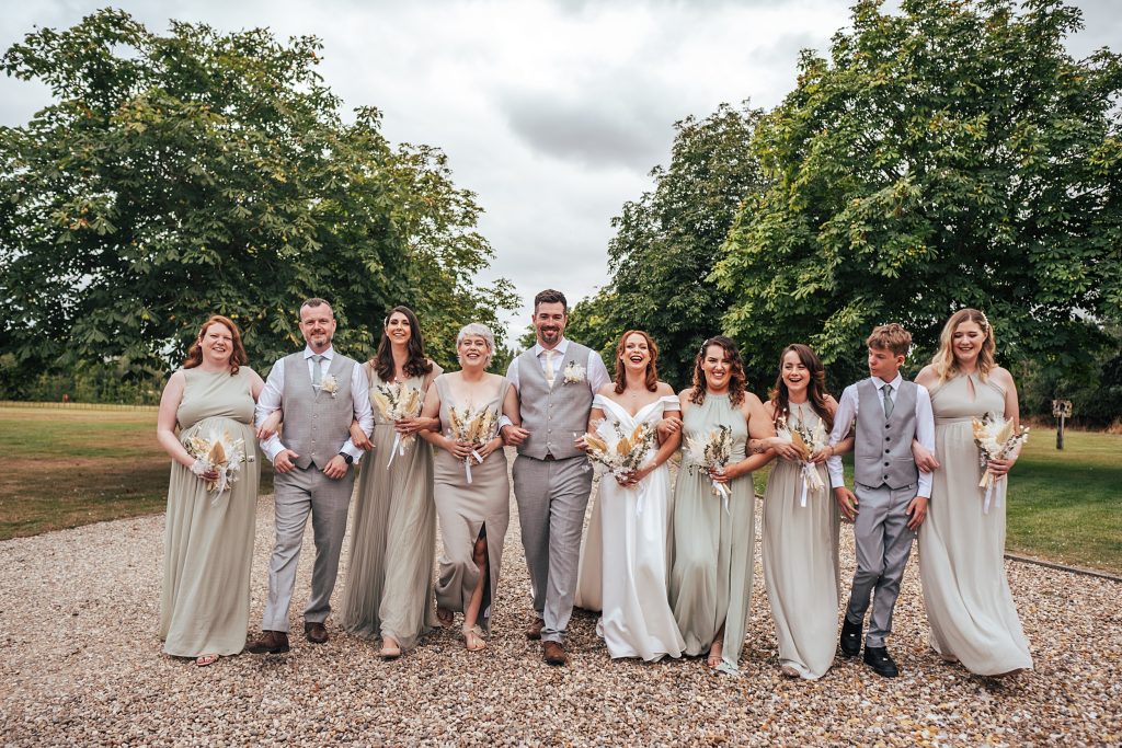 bride and groom with wedding party walk treelined driveway
