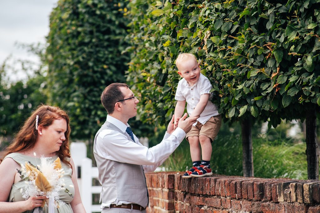 man helps little boy off of a wall