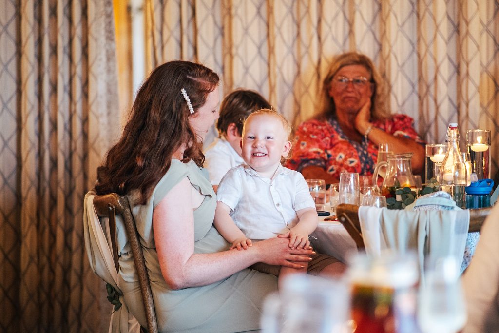 little boy laughs on mums lap during speech