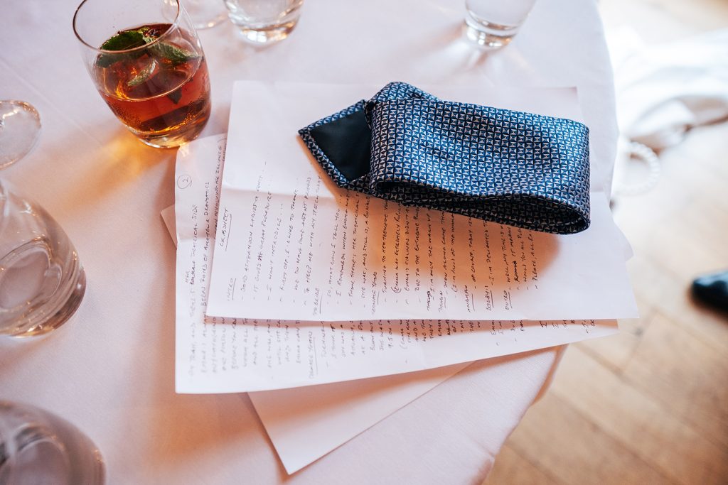 close up of speech on table with a drink and discarded tie