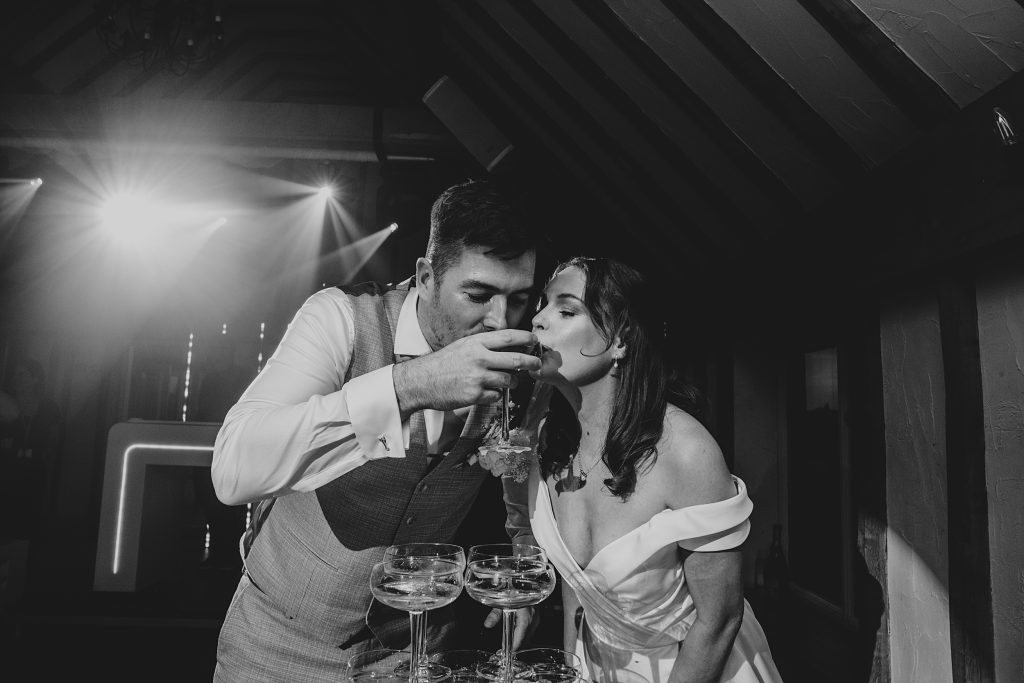 bride and groom sip from champagne tower