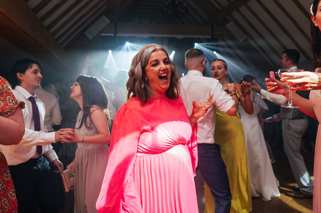 wedding guest sings on dance floor and holds martini glass