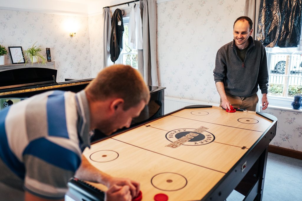 Groom plays air hockey with groomsmen before wedding
