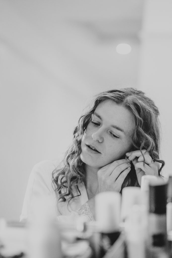 bride's reflection as she puts in earrings