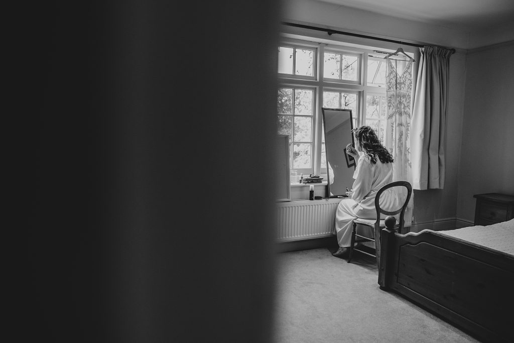 shot of bride doing make up from the bedroom door