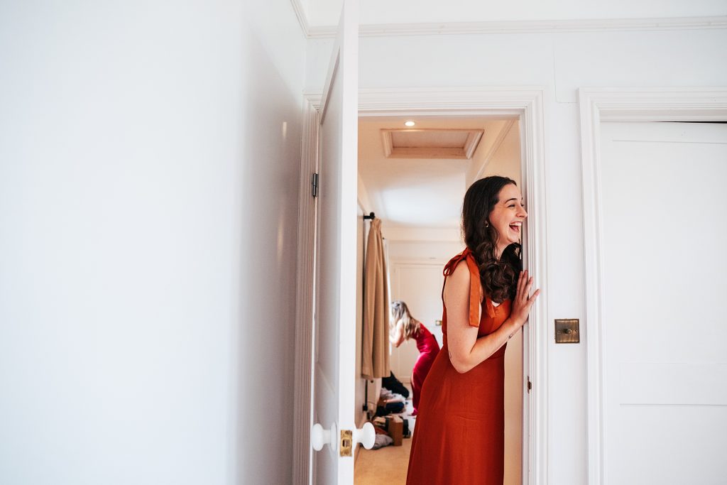 bridesmaid leans in doorway and laughs
