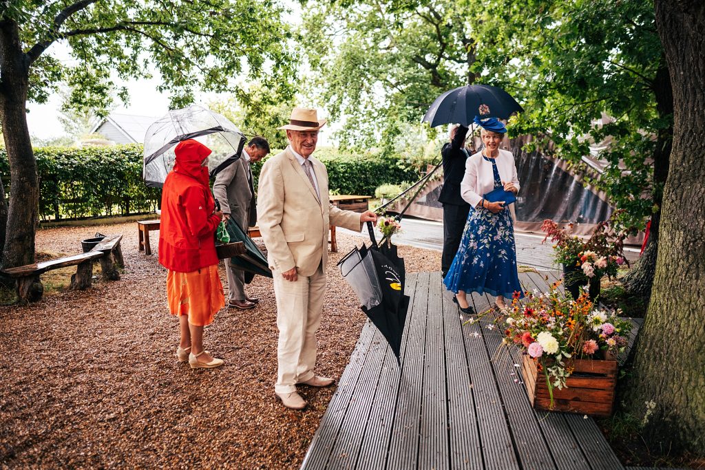 guests arriving for a wedding with raincoats and umbrellas