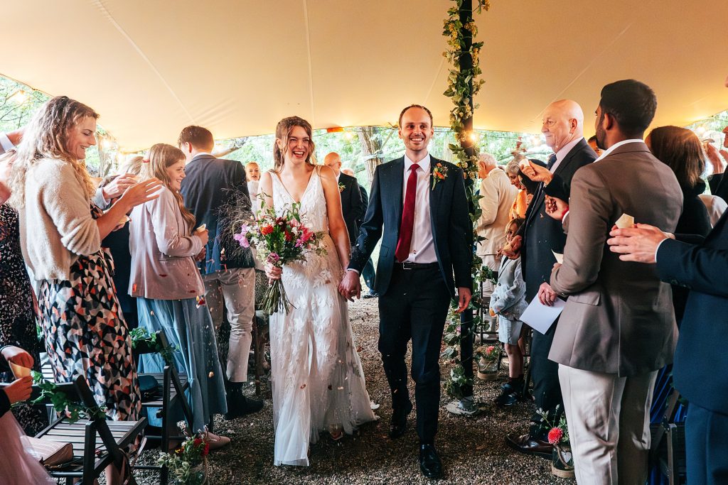 bride and groom walk back up aisle as guests throw confetti