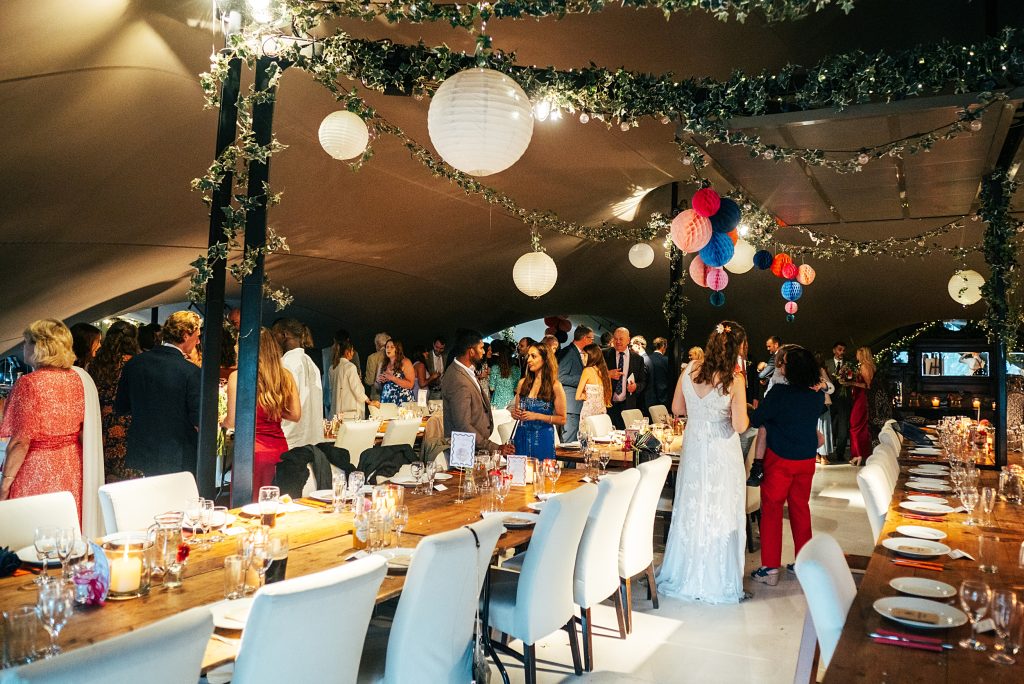 wedding guests mingle in stretch tent