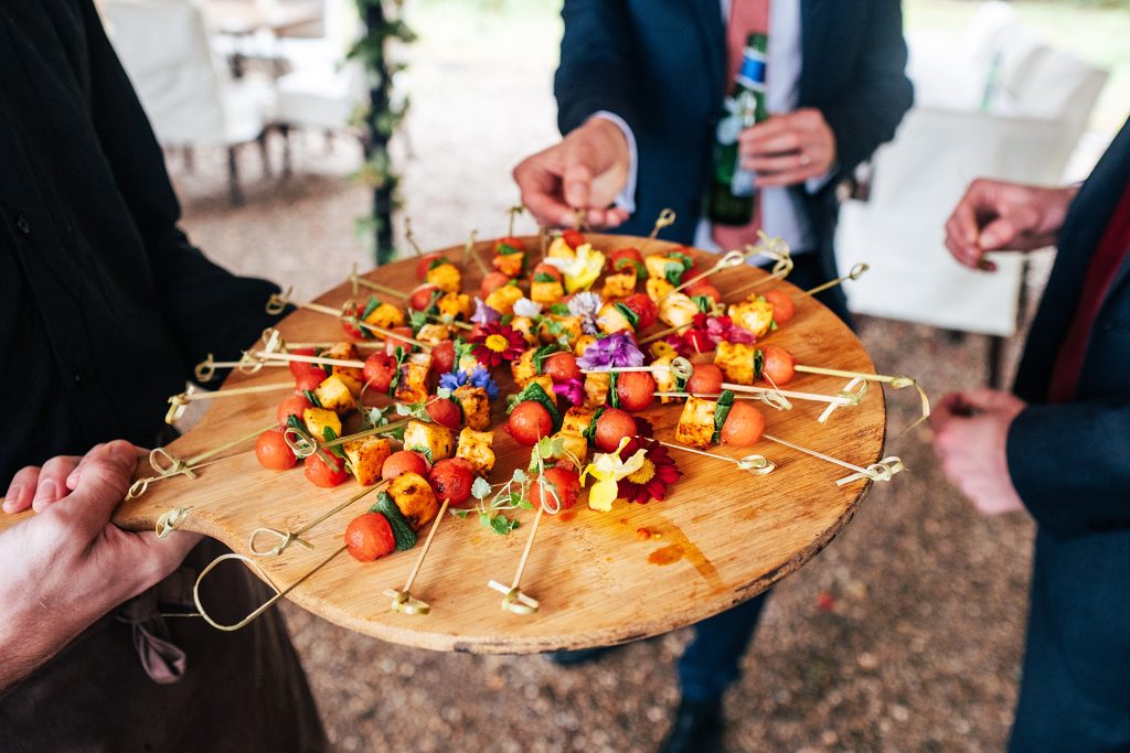wedding guests take kebabs from a server
