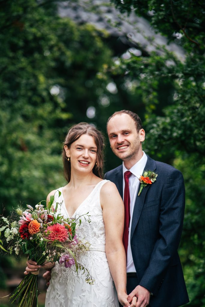 smiling bride and groom stand in a garden