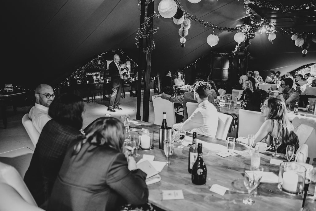 wedding guests listen to speech in stretch tent