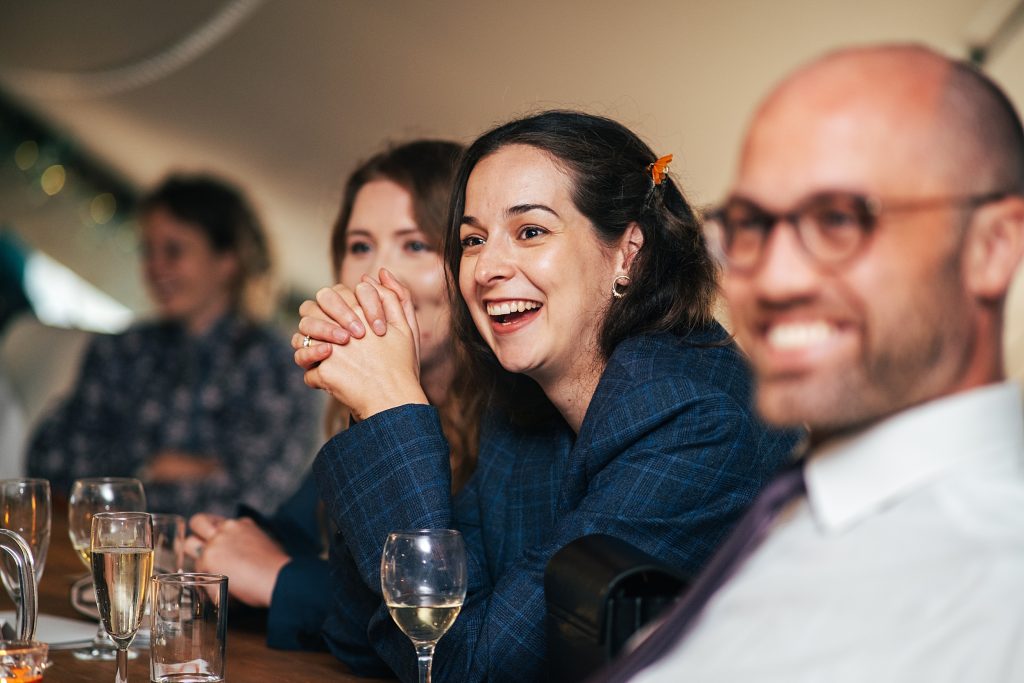 bridesmaid in groomsmens jacket laughs at speech
