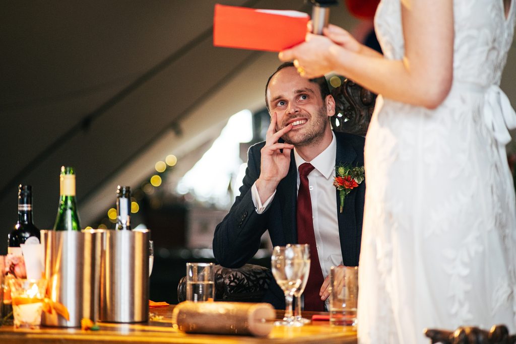 groom looks up at bride as she gives speech