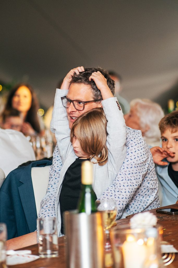 little boy reaches up and plays with dads hair whilst listening to speech