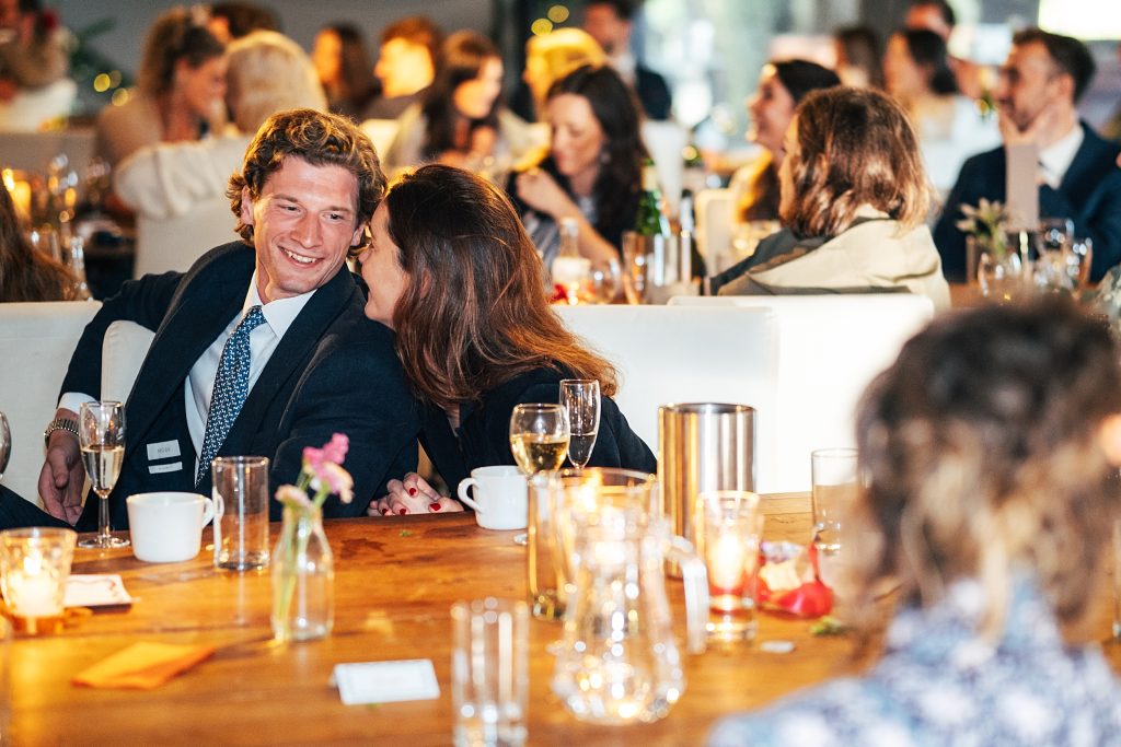 wedding guest whispers in her partners ear during speech