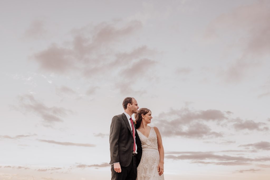 bride and groom against a cloudy evening sky