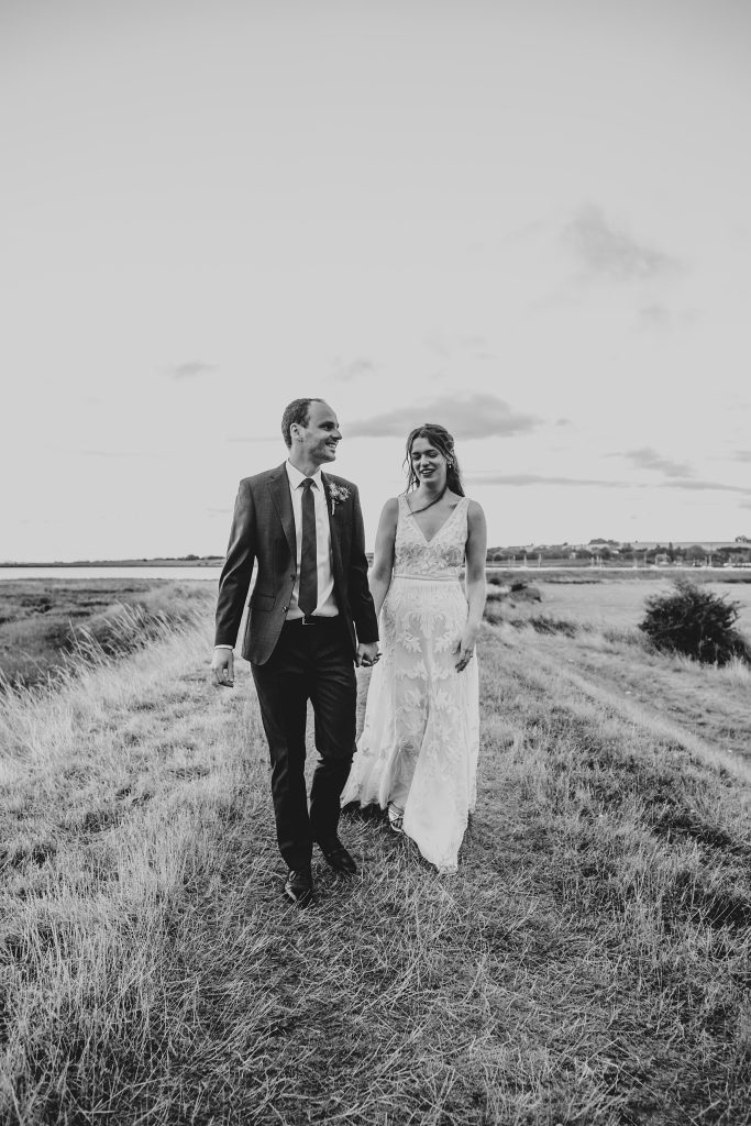 bride and groom walk on headland away from coast