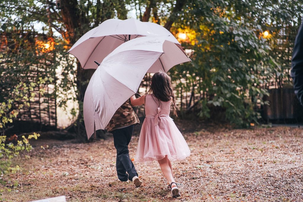 two kids run with pink umbrellas