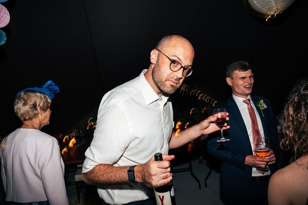wedding guest on dance floor with bottle and glass in hands