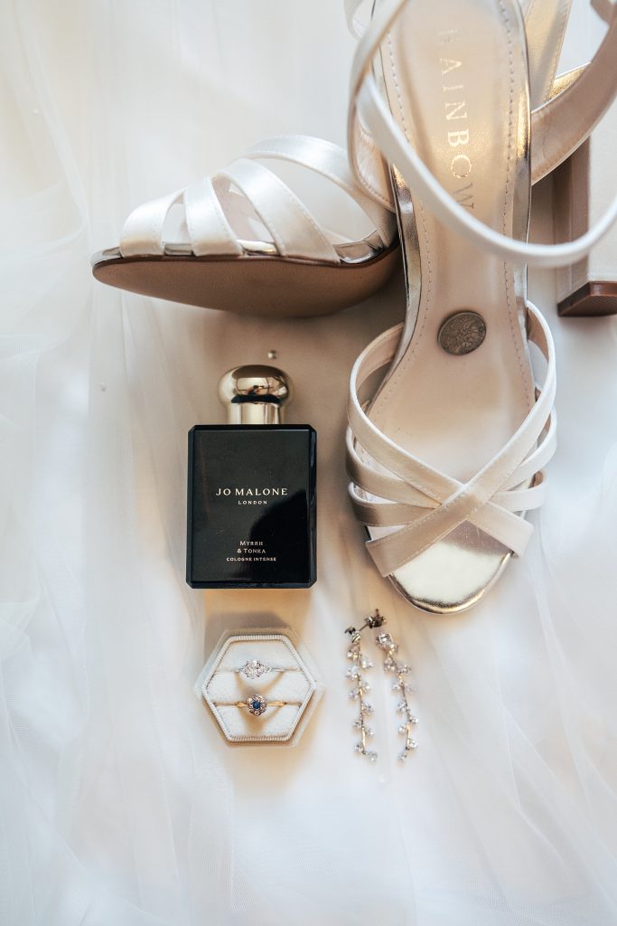 flat lay of bridal shoes, perfume, jewellery